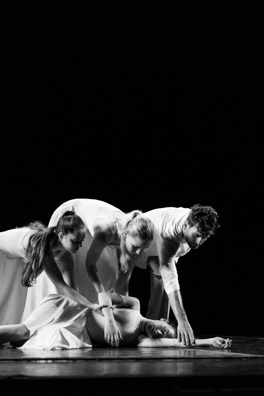tre danzatori vestiti di bianco inginocchiati