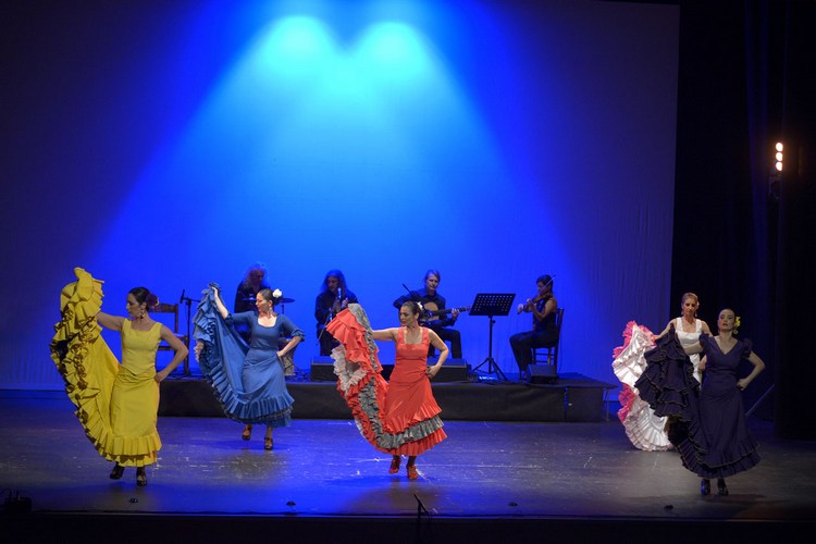 cinque donne con le gonne tipiche della danza flamenca, la bata de cola, accompagnate in scena da alcuni musicisti